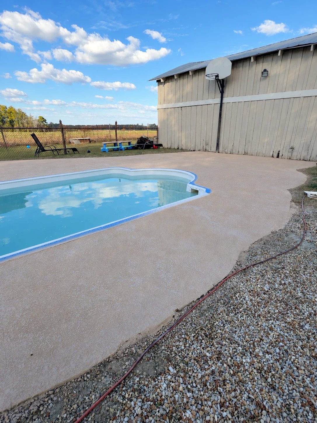 Restored textured concrete around a pool, running up to the outbuilding