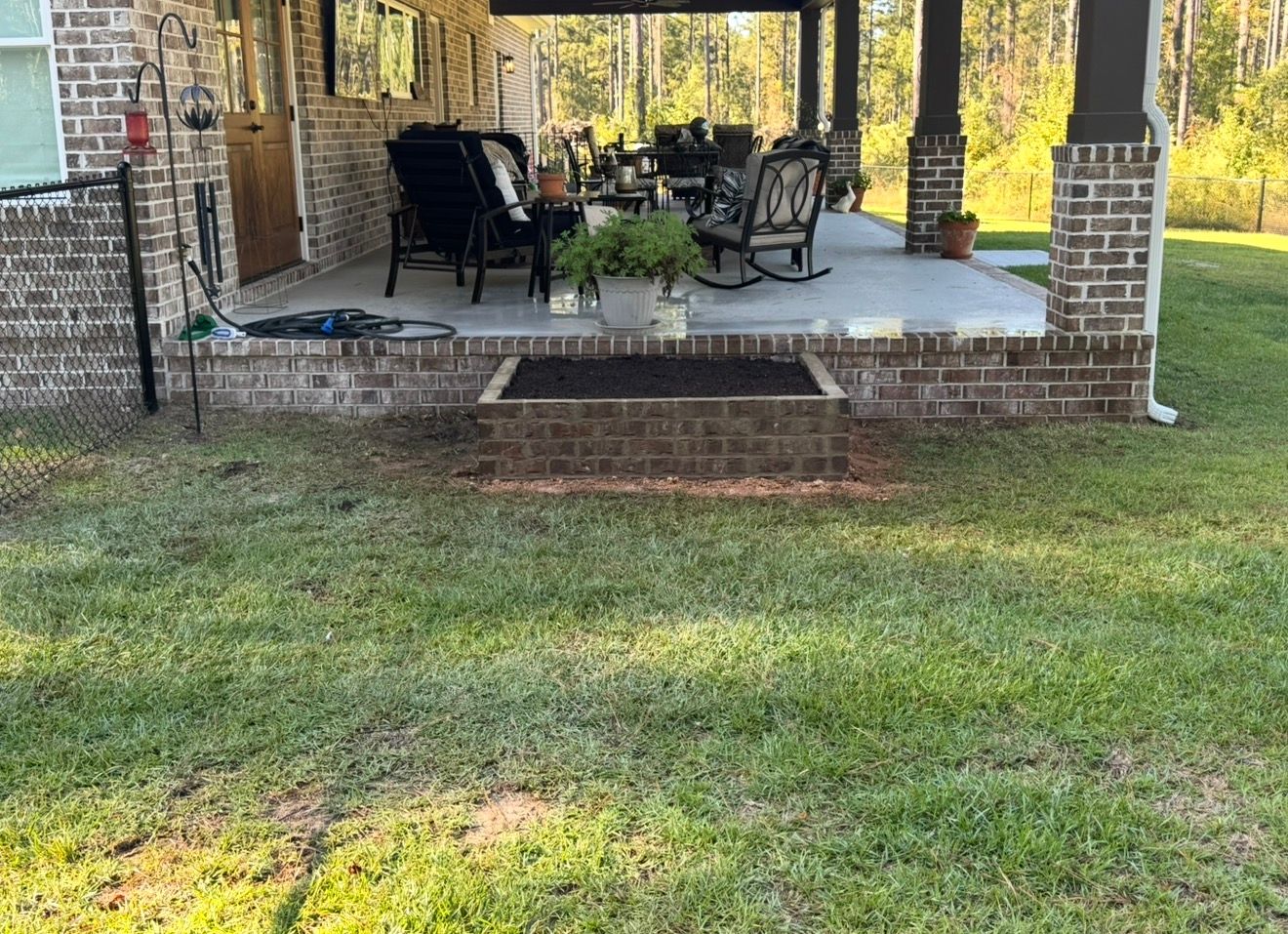 Covered brick patio with a restored concrete floor and a brick planter