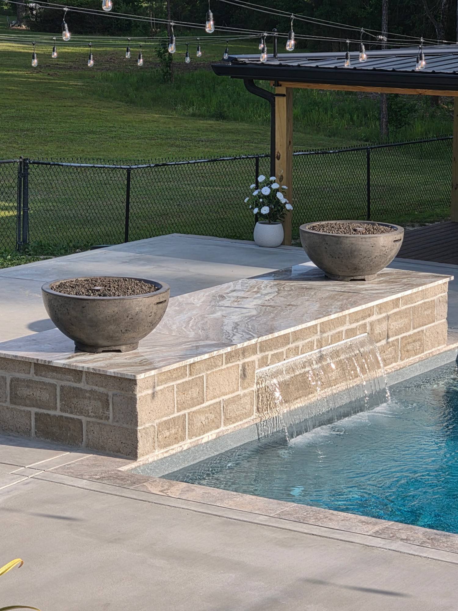 Fire bowls and sheer descent water feature spilling into a pool